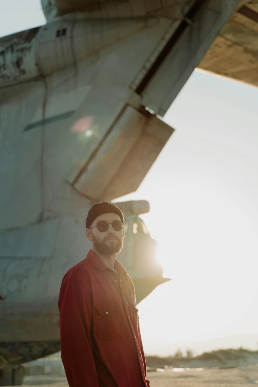 a man standing in front of an airplane, an album cover, by Winona Nelson, pexels contest winner, light beard, beret and sunglasses, geometry, big red sun