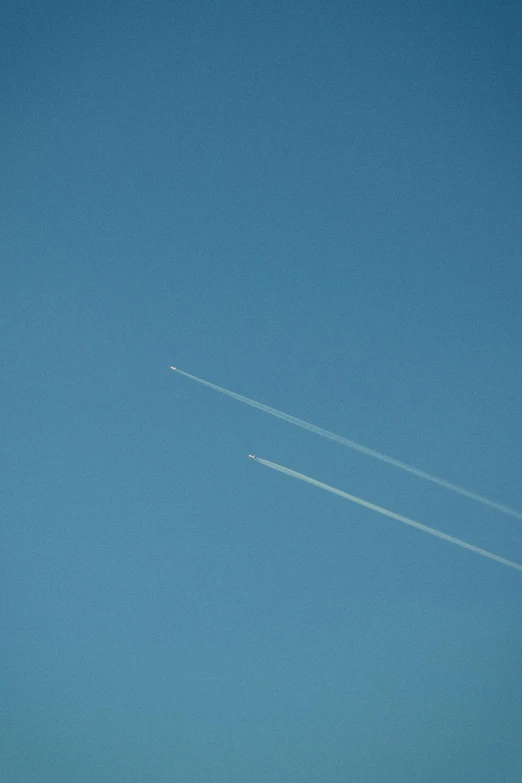 a couple of airplanes flying through a blue sky, by Peter Churcher, postminimalism, clear lines!!, planets in the skies, devils, midday photograph