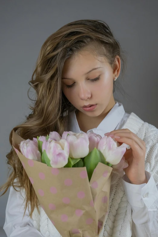 a woman holding a bouquet of pink and white tulips, a colorized photo, inspired by Gerard David, young teen, pouty, on a gray background, white sleeves