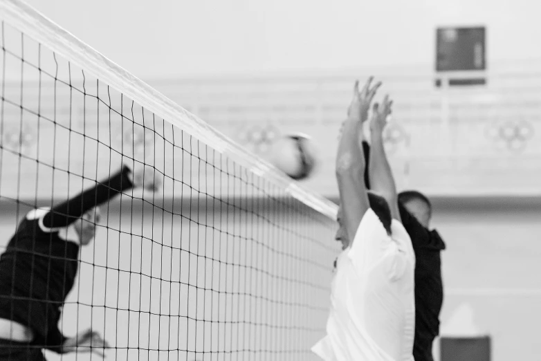 a couple of men playing a game of volleyball, a black and white photo, unsplash, square, usa volleyball, netting, video footage