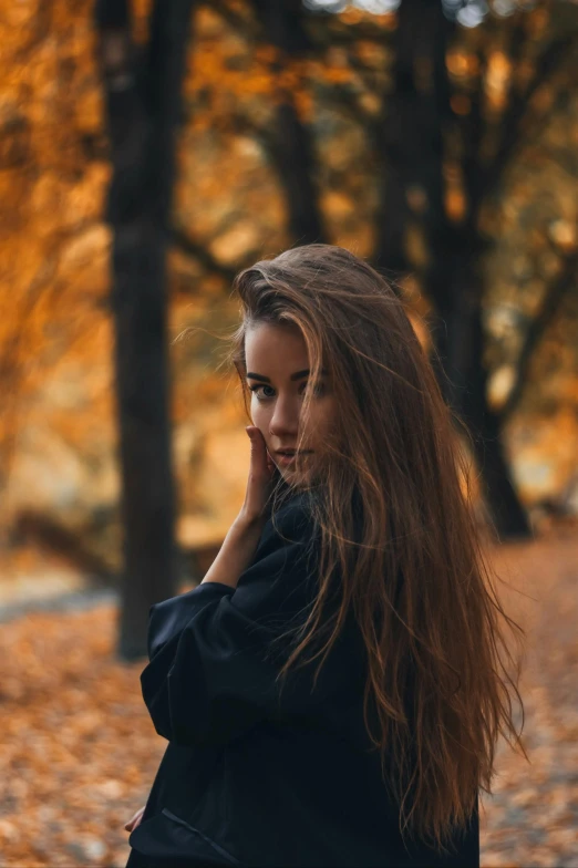 a woman sitting on a bench in a park, a picture, by irakli nadar, pexels contest winner, renaissance, orange and brown leaves for hair, dark brown flowing long hair, portrait featured on unsplash, 🤤 girl portrait