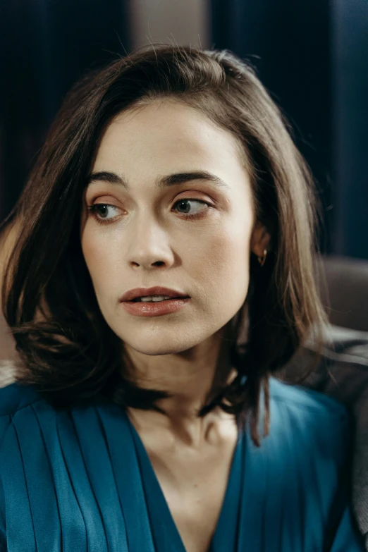 a woman in a blue dress sitting on a couch, a character portrait, inspired by Louisa Matthíasdóttir, trending on pexels, antipodeans, olga kurylenko, exhausted face close up, strong jawline, acting headshot