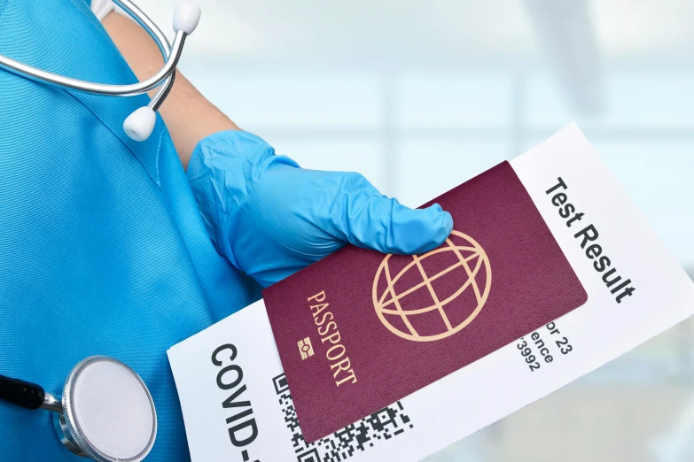 a person in a blue scrub suit holding a passport and a stethoscope, coronavirus, cover image, traveller, thumbnail