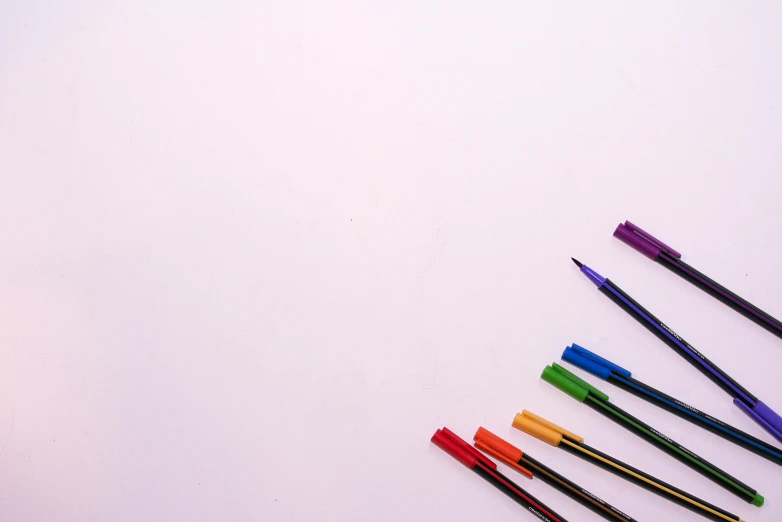 a group of pens sitting on top of a white surface, a minimalist painting, by Gina Pellón, pexels, purple neon colours, background image, color image, multicolor