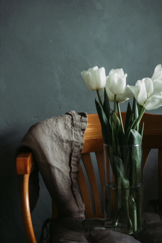 a vase filled with white flowers sitting on top of a wooden chair, a still life, pexels contest winner, tulips, dirty linen robes, muted colors with minimalism, comfy chairs