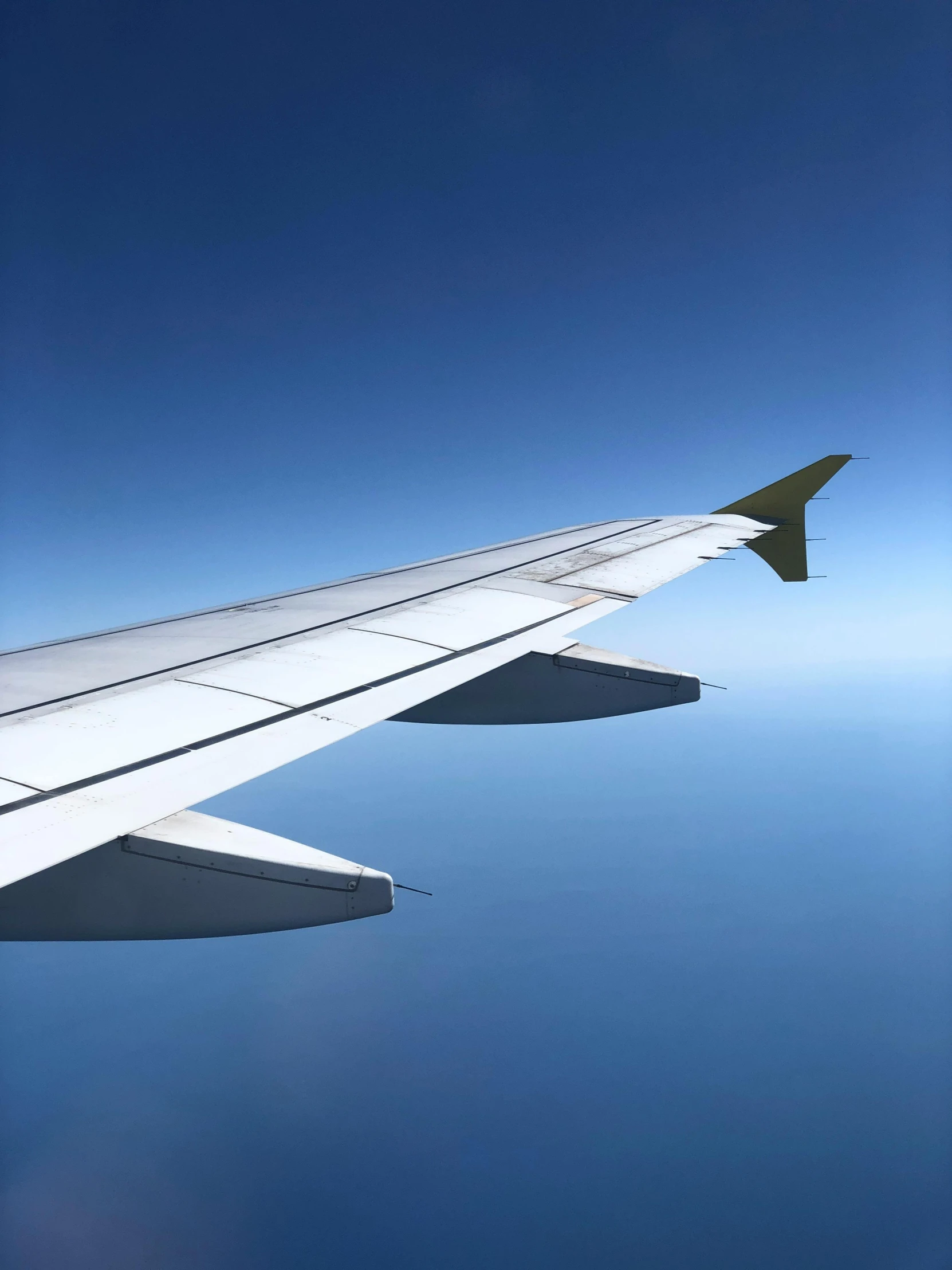 the wing of an airplane flying in the sky, by Daren Bader, pexels contest winner, hurufiyya, plain background, modeled, clear blue skies, detailed and complex