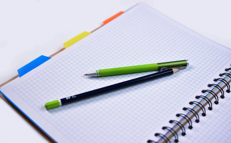 a green pen sitting on top of a notebook, pexels, square lines, multicoloured, educational supplies, 9 9 designs