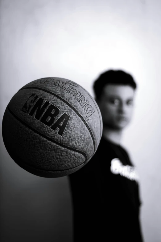 a black and white photo of a man holding a basketball, an album cover, inspired by Mia Brownell, wenjun lin, slightly blurred, serious business, 1 6 years old