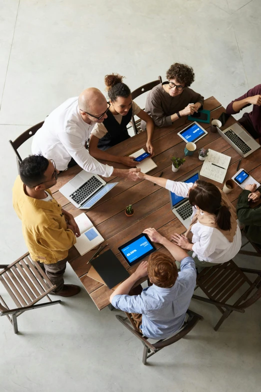 a group of people sitting around a wooden table, a digital rendering, trending on pexels, square, centered design, professional image, aerial shot