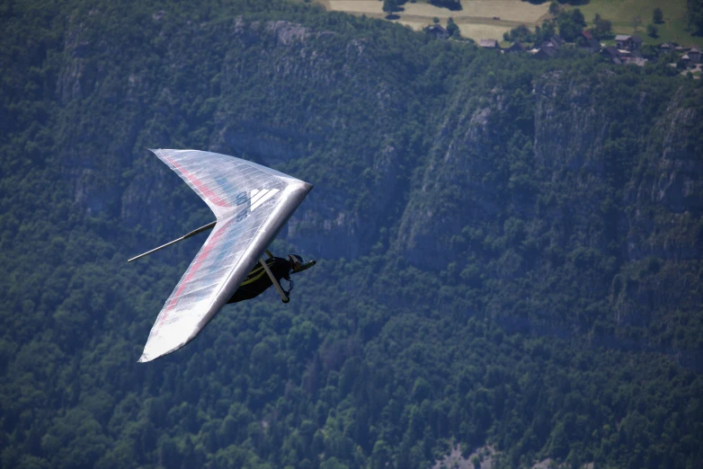 a man flying a hang glider over a lush green hillside, by David Simpson, pexels contest winner, figuration libre, fjords, profile picture 1024px, jet wings on the back, over a chalk cliff