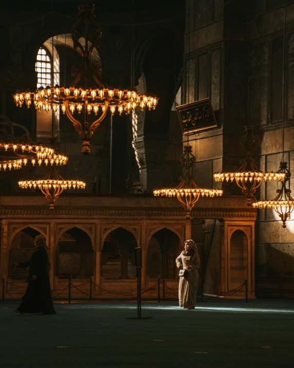 a man standing in front of a chandelier in a building, unsplash contest winner, hurufiyya, holy ceremony, gif, istanbul, taken in the late 2010s
