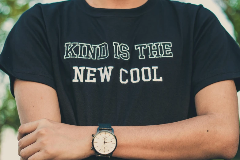 a man wearing a shirt that says kind is the new cool, by Niko Henrichon, trending on unsplash, aestheticism, watch photo, background image