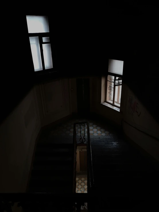 a staircase in a dark room with two windows, looking down on the camera, anna nikonova, low quality photo, inside building