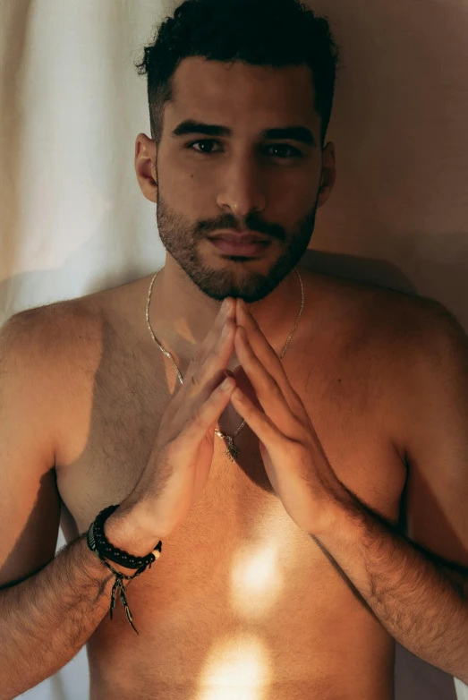 a shirtless man standing in front of a white curtain, an album cover, by Elsa Bleda, trending on pexels, wears a egyptian ankh necklace, young spanish man, drake, gay