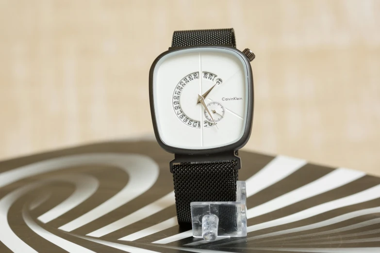 a close up of a wrist watch on a table, a stipple, inspired by jeonseok lee, unsplash, minimalism, square, clear curvy details, caravagio, 1961”