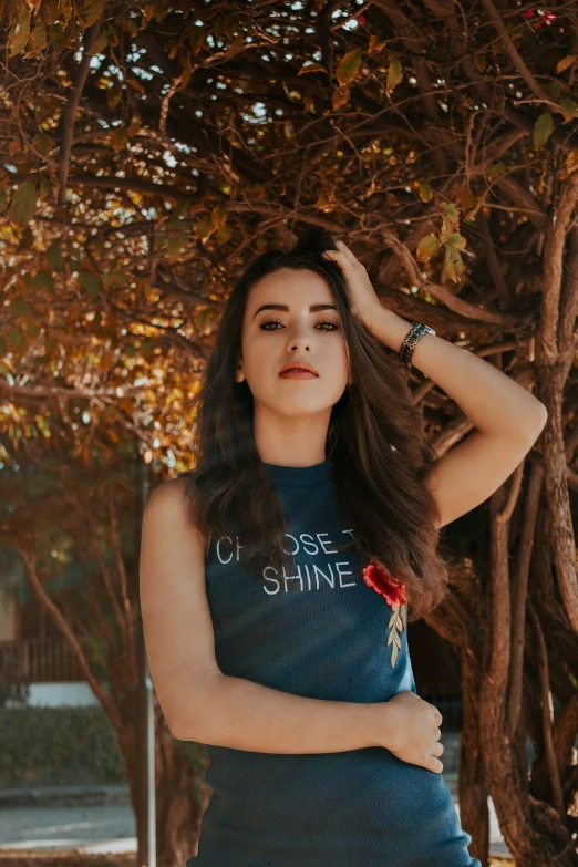 a woman standing in front of a tree, a colorized photo, trending on pexels, tachisme, chloe bennet, wearing tank top, beautiful iranian woman, shining lights