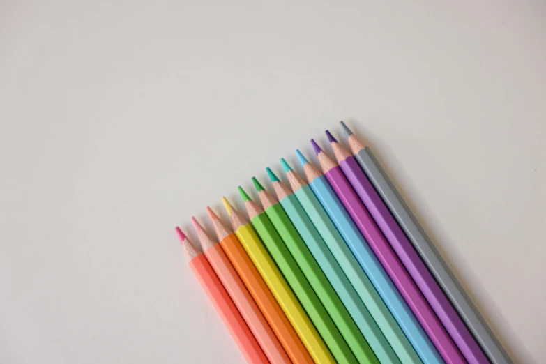 a group of colored pencils sitting on top of a white surface, a color pencil sketch, by Carey Morris, pexels, neon pastel, on a pale background, colourised, minimalist photo