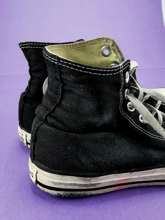 a pair of black sneakers on a purple surface, featured on reddit, auto-destructive art, 1990 photograph, bottom view, tall shot, double layer fold over hem