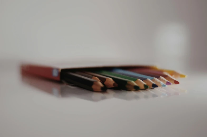 a group of colored pencils sitting on top of a table, pexels contest winner, hyperrealism, brown, with a white background, close-up shot taken from behind, rectangular piece of art