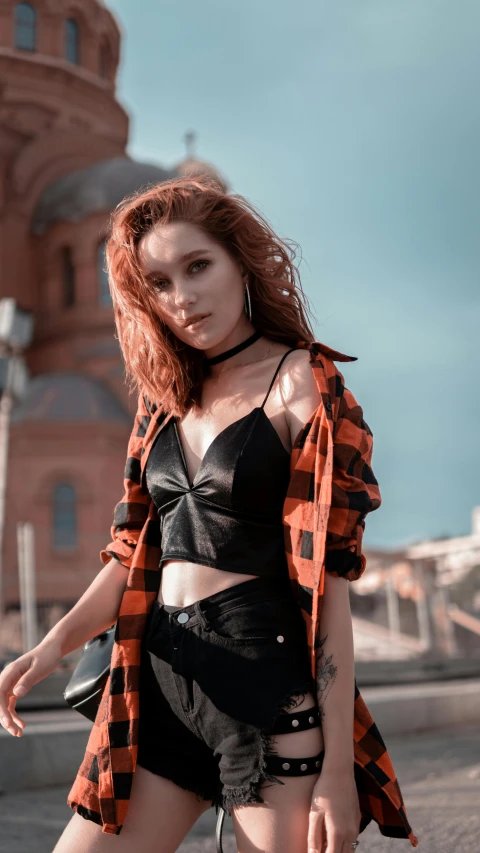 a woman posing for a picture in front of a building, trending on pexels, renaissance, croptop, black and orange, metal garments, reddish hair