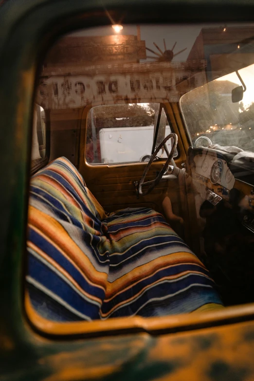 a close up of a seat in a vehicle, an album cover, by Jessie Algie, unsplash, peru, covered with blanket, old rusty pickup - truck, interior of a small