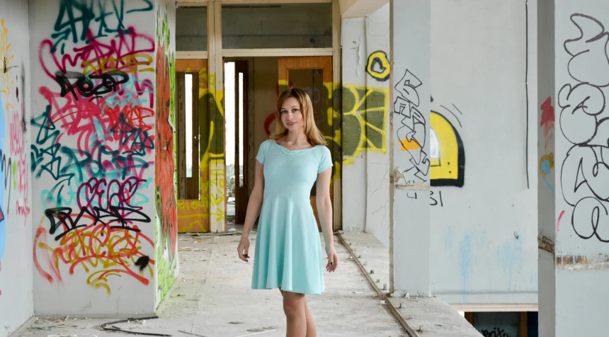 a woman standing in a room with graffiti on the walls, inspired by Adrienn Henczné Deák, pexels contest winner, light green dress, pastel blue, demolition, 15081959 21121991 01012000 4k