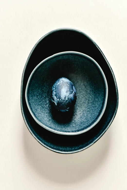 a couple of bowls sitting on top of a table, dark black porcelain skin, indigo, translucent eggs, detail shot