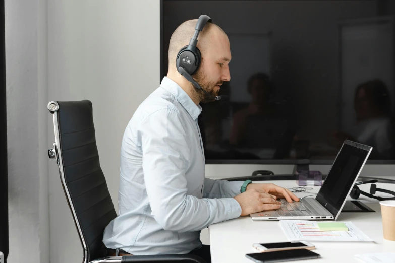 a man sitting at a desk with a laptop and headphones on, by Adam Marczyński, hurufiyya, in an call centre office, profile photo, office clothes, anato finnstark and kelogsloops