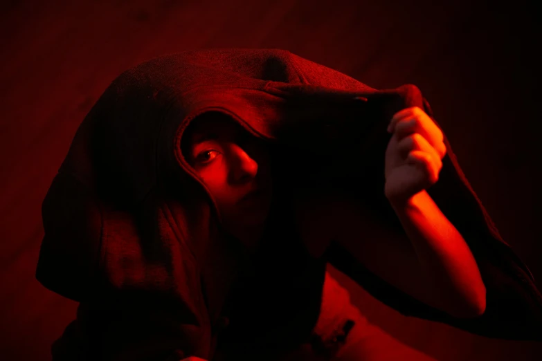 a person with a hood over their head, inspired by Henry Fuseli, pexels contest winner, detailed red lighting, crouching, press shot, close - up photograph