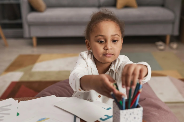 a little girl sitting on the floor drawing with colored pencils, inspired by Sophia Beale, pexels contest winner, visual art, african american girl, rectangle, holding it out to the camera, no artefacts