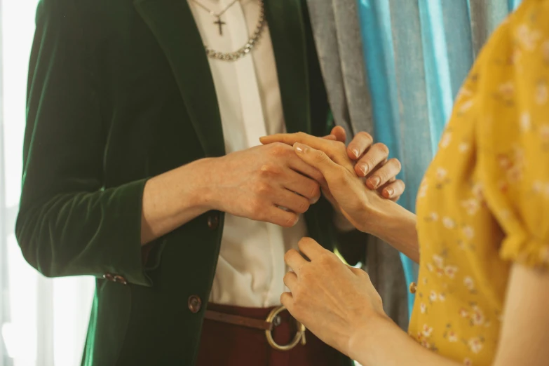 a man putting a ring on a woman's finger, a colorized photo, trending on pexels, green and brown clothes, wes anderson style, holding each other hands, tall thin