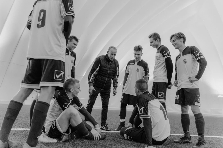 a group of young men sitting on top of a soccer field, a black and white photo, inspired by Mihály Zichy, pexels contest winner, calmly conversing 8k, hexadome, monochrome:-2, performance