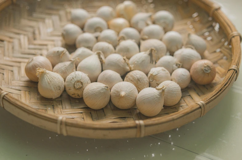 a basket filled with onions sitting on top of a table, metaballs, coconuts, background image, alessio albi