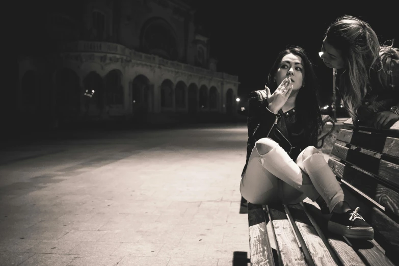 a couple of women sitting on top of a wooden bench, a black and white photo, pexels contest winner, graffiti, nigth, outside alone smoking weed, gothic girl smoking, tourist photo