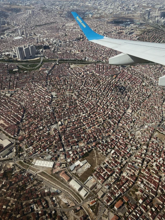 the wing of an airplane flying over a city, happening, istanbul, highly detailed # no filter, gigapixel photo, red roofs