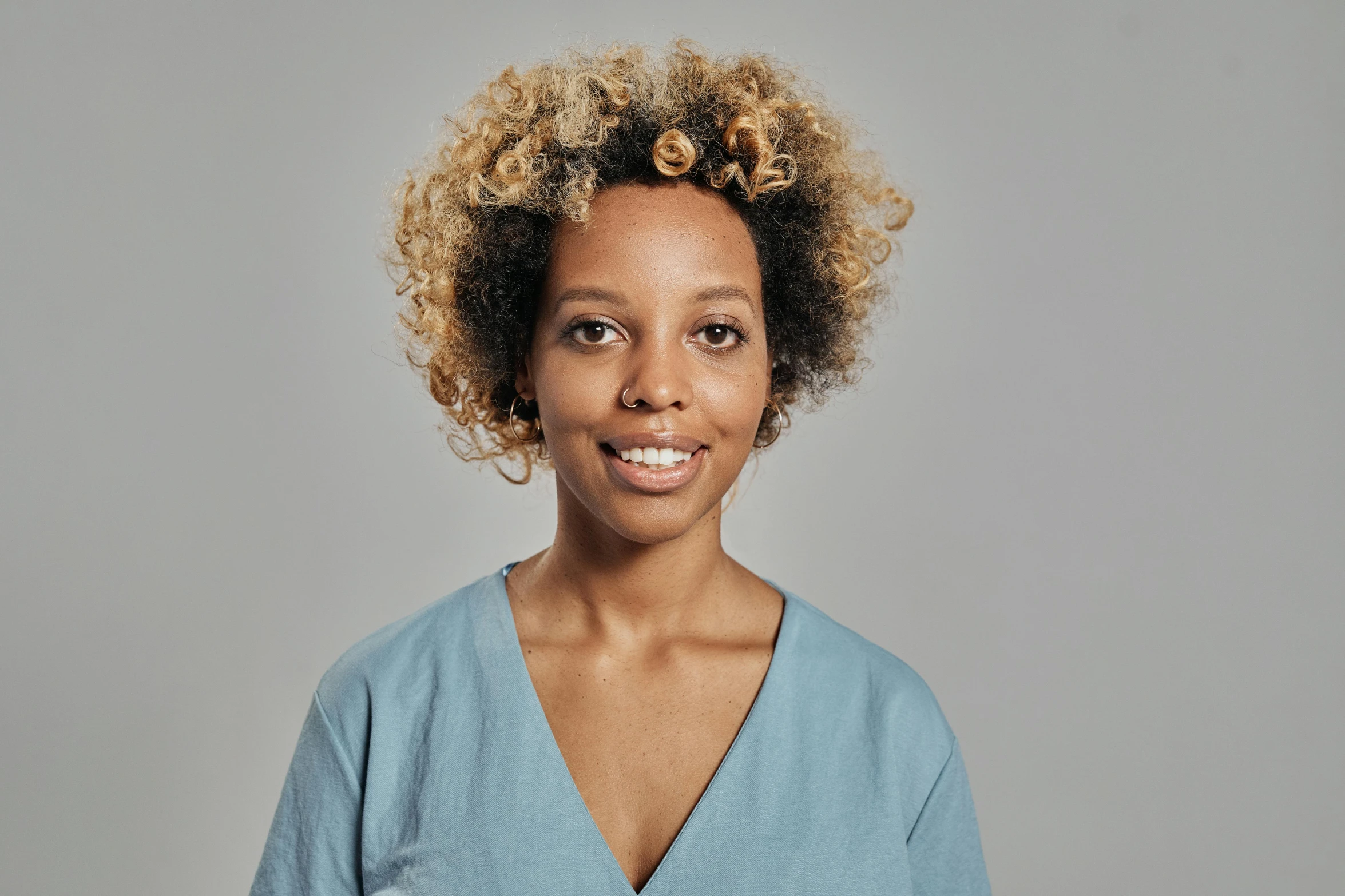 a woman with curly hair posing for a picture, les nabis, plain background, cerulean, light brown skin, architect