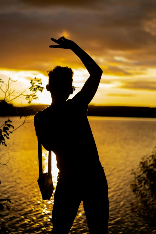 a silhouette of a man throwing a frisbee at sunset, by Jesper Knudsen, happening, doing a sassy pose, lake view, ((sunset)), music video