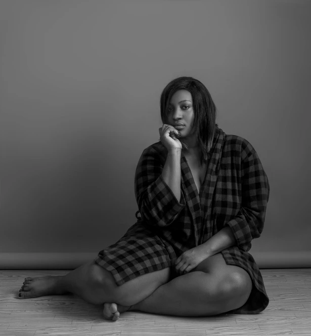 a black and white photo of a woman sitting on the floor, unsplash, hyperrealism, alluring plus sized model, flannel, photo of a black woman, wearing a simple robe