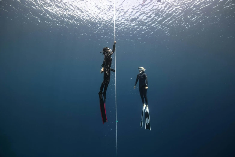 a couple of people that are in the water, bottom of ocean, hanging, titanium, 2 meters