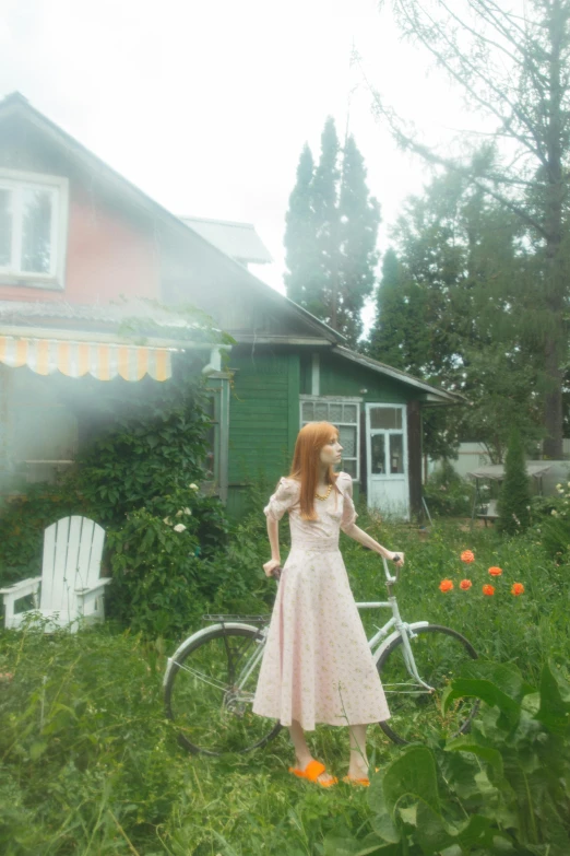 a woman in a pink dress standing next to a bike, an album cover, inspired by Oleg Oprisco, pexels contest winner, magic realism, in front of the house, midsommar - t, a redheaded young woman, cinematic shot ar 9:16 -n 6 -g
