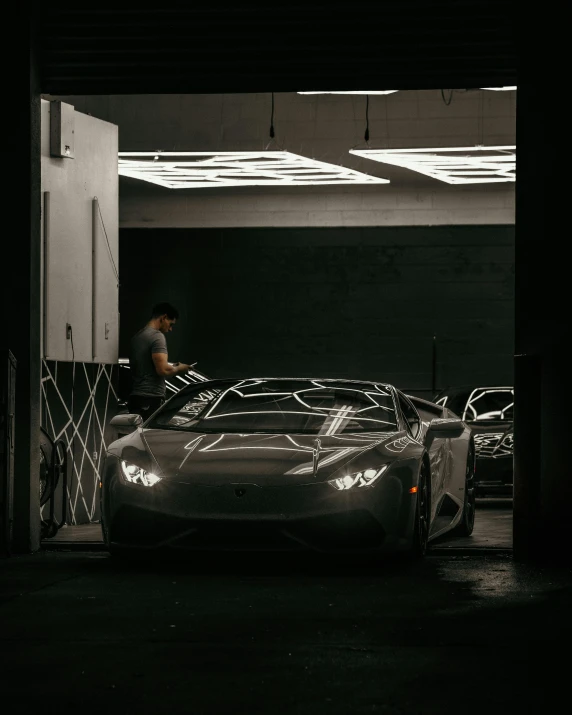 a man standing next to a car in a garage, pexels contest winner, hypermodernism, lamborghini, busy night, gif