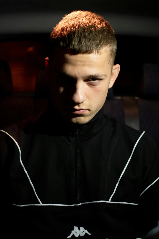 a man sitting in a car looking at his cell phone, an album cover, by artist, trending on reddit, he looks like tye sheridan, intense stare, wearing a track suit, in a nightclub