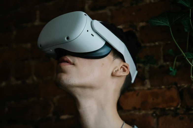 a man wearing a virtual reality headset in front of a brick wall, trending on pexels, hyperrealism, white helmet, gaming, facebook post, wearing goggles