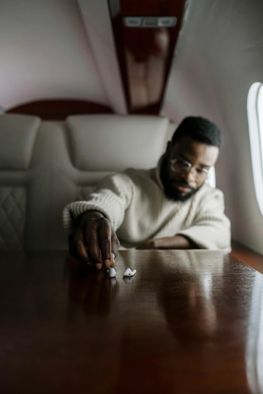 a man sitting at a table in an airplane, an album cover, by artist, pexels contest winner, jaylen brown, offering the viewer a pill, wealthy, isolation