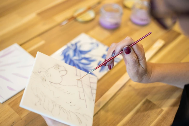 a woman is drawing a picture on a piece of paper, a detailed painting, inspired by Adélaïde Labille-Guiard, instagram, delftware, indigo and red iron oxide, on canvas, ilustration