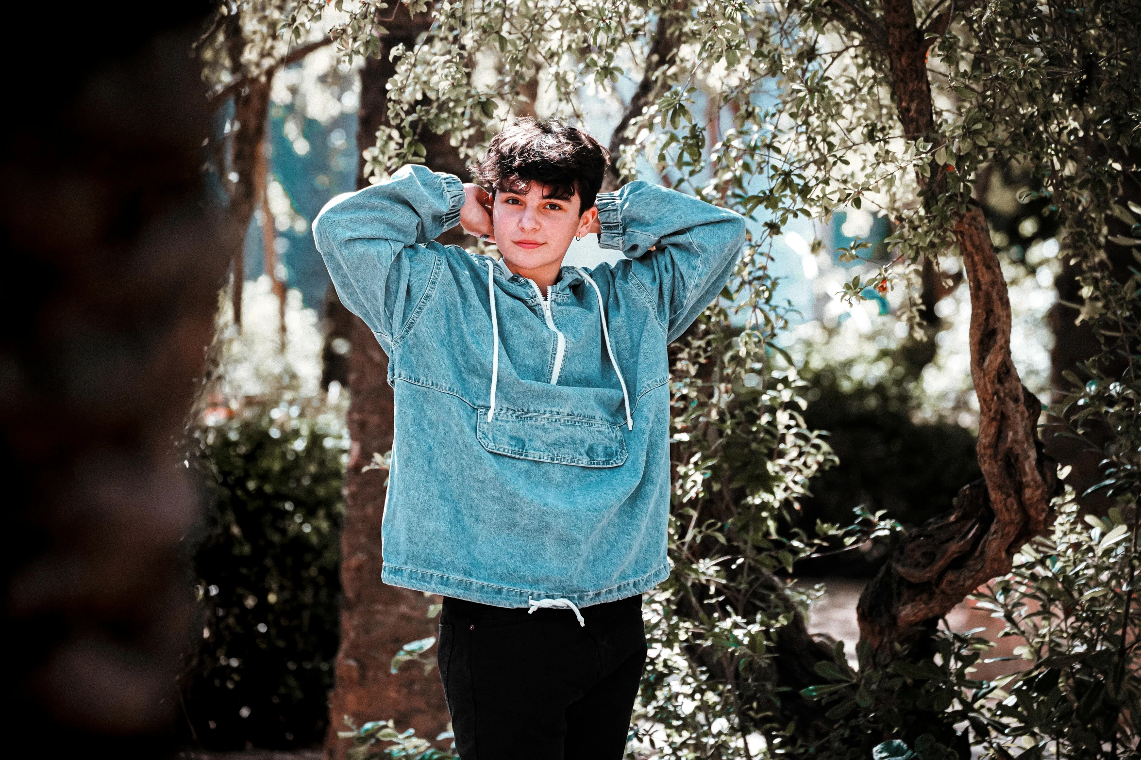 a young man standing in front of a tree, an album cover, pexels, realism, denim, 14 yo berber boy, wearing a track suit, cute boys