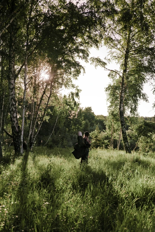 a man walking through a lush green forest, an album cover, unsplash, romanticism, in a large grassy green field, sun lit, in scotland, cinematic outfit photo