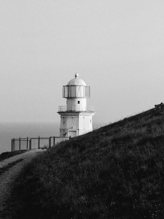 a black and white photo of a lighthouse on a hill, unsplash, minimalism, soft light - n 9, rusty, shot on iphone, lantern light besides