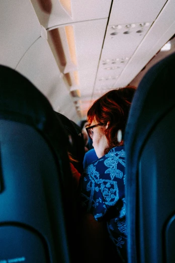 a woman sitting in the aisle of an airplane, pexels contest winner, happening, back turned, jen atkin, max dennison, spying discretly