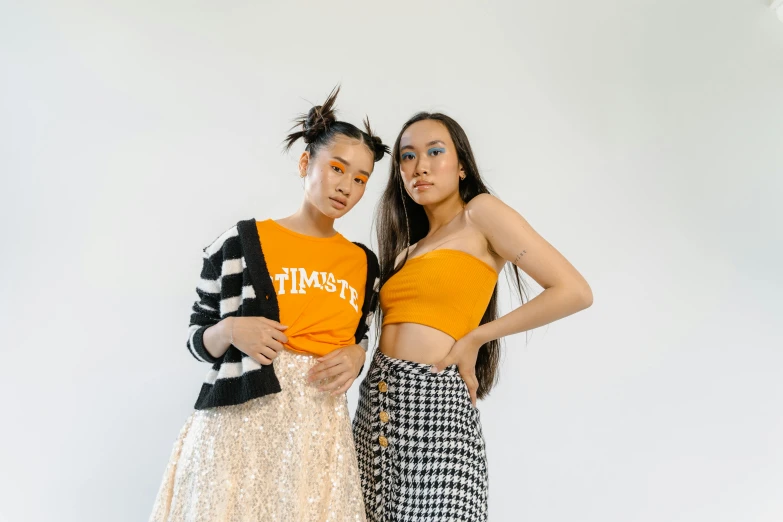 a couple of women standing next to each other, inspired by Wang Duo, trending on pexels, croptop, black and orange, resembling a mix of grimes, asian descent